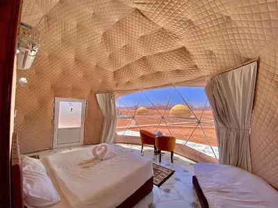 a bedroom with two beds and a large window at Desert Star of Wadi Rum in Wadi Rum
