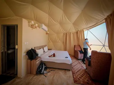 a man standing in a room with a bed in a tent at Desert Star of Wadi Rum in Wadi Rum