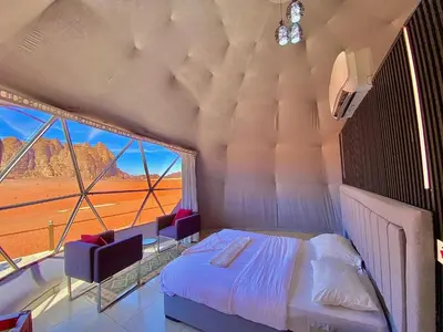 a bedroom with a bed and a large window at Desert Star of Wadi Rum in Wadi Rum