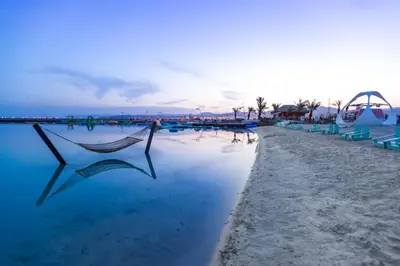 a hammock is sitting on the beach near the water at Ayla and chill Restricted to families and couples only in Aqaba