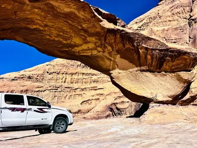 a white truck parked in front of a rock formation at Al-Shakriya Village Camp in Wadi Rum