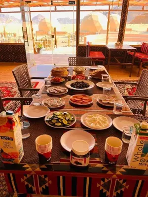 a table with plates of food and cups on it at Whispering Rum in Wadi Rum