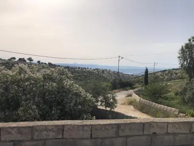a stone wall next to a road with mountains in the background at Pasha's house in Balad al Manşūrah