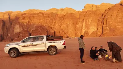 a group of people standing around a white truck in the desert at Rayyan Bedouin life camp in Wadi Rum