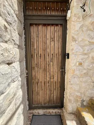 a wooden door in a stone building with a gate at Al Karak House in Kerak