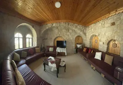 a living room with leather couches and a stone wall at Al Karak House in Kerak
