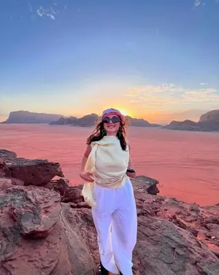 a woman standing on the rocks near the water at Hakon Matata Wadi Rum Jeep Tours Camp in Wadi Rum