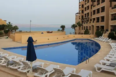 a swimming pool with lounge chairs and an umbrella at Samarah Dead Sea Resort Apartment with Sea View FP4 Traveler Award 2025 Winner Thursday, Friday & Saturday Groups consisting solely of male guests are not permitted in Sowayma
