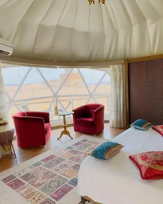 a bedroom with two chairs and a bed and a large window at Wadi Rum The ARC camp in Wadi Rum