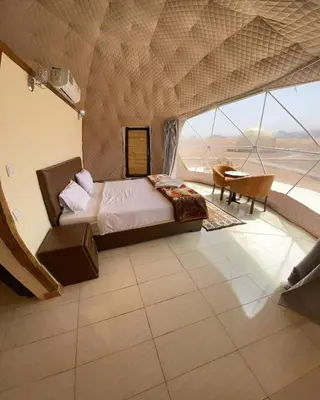 a bedroom with a bed and a large window at Wadi Rum The ARC camp in Wadi Rum