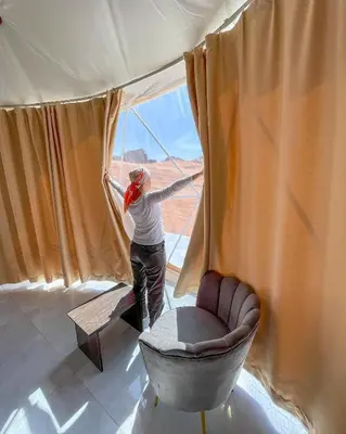 a woman looking out of a window at the desert at Wadi Rum Calma camp in Aqaba