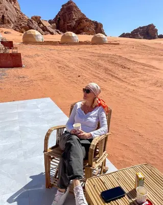 a woman sitting in a chair in the desert at Wadi Rum Calma camp in Aqaba