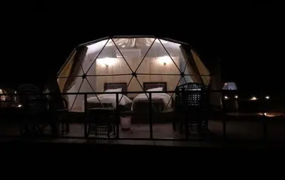 a room with chairs and a tent at night at Echo Desert Camp in Wadi Rum
