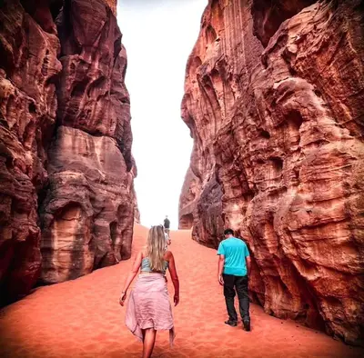 a man and a woman walking through a canyon at LARA lUXURY CAMP in Wadi Rum