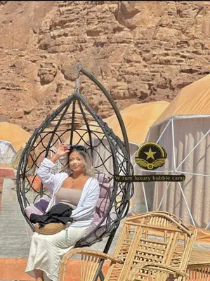 a woman sitting in a swing in a desert at RUM W BUBBLE lUXURY CAMP in Wadi Rum