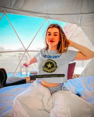 a woman sitting on a bed in a tent at RUM W BUBBLE lUXURY CAMP in Wadi Rum