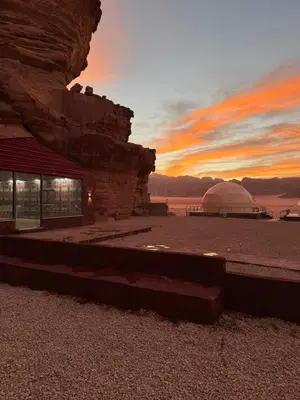 a building in the desert with a sunset in the background at Red Twilight Camp in Disah