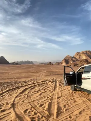 a car parked in the desert with its door open at Red Twilight Camp in Disah