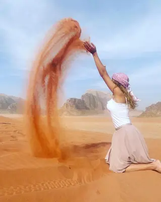 a woman sitting in the desert with her hand in the air at wadirumtours&camp in Wadi Rum