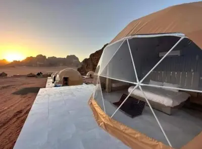 a tent in the desert with a bed and a sunset at Wadi Rum Gulf camp in Aqaba