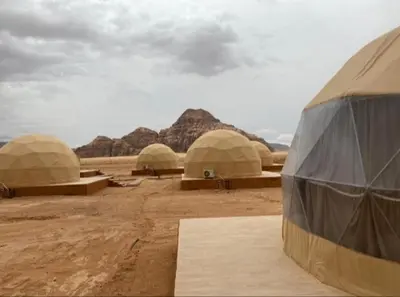 a group of domes in the desert with mountains at Wadi Rum Gulf camp in Aqaba