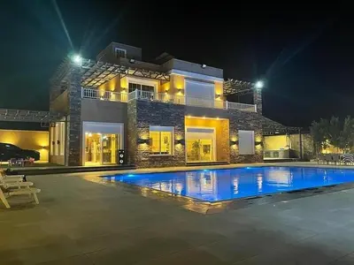 a large swimming pool in front of a house at night at Taj Villa 1 deadsea - Entire Villa with sea view in Sowayma