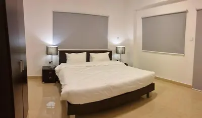 a bedroom with a bed with white sheets and two lamps at Byblos Deluxe in Aqaba