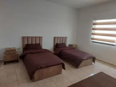 a bedroom with two beds and a window at Cozy Home 4 in Amman