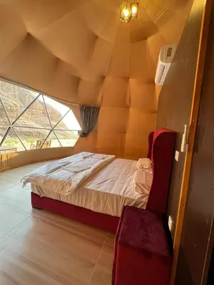a bedroom with a bed and a chair in a room at Bedouin Secret Camp in Wadi Rum