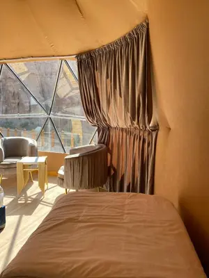 a bedroom with a bed and a large window at Bedouin Secret Camp in Wadi Rum