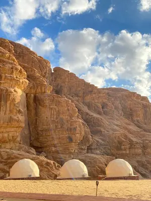 two domes in the desert next to a mountain at Bedouin Secret Camp in Wadi Rum
