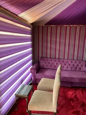 a purple couch and a stool in a room at wadi Rum bissan camp in Wadi Rum