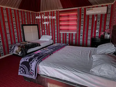 two beds in a room with red and white wallpaper at wadi Rum bissan camp in Wadi Rum