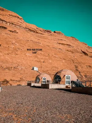 two domes sitting in front of a mountain at wadi Rum bissan camp in Wadi Rum