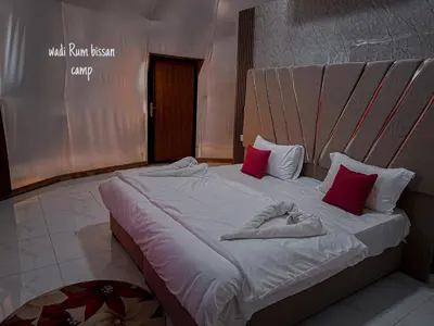 a large bed with red and white pillows on it at wadi Rum bissan camp in Wadi Rum