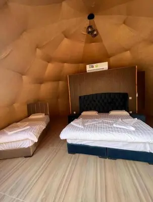 two beds in a room with a wooden ceiling at HILTON WADi RUM in Disah