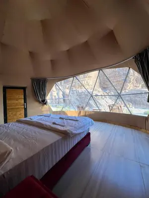 a large bed in a room with a large window at HILTON WADi RUM in Disah