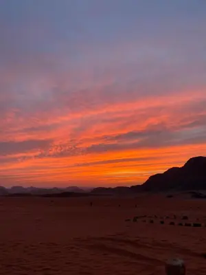a sunset in the desert with mountains in the background at Desert Gate Camp in Wadi Rum