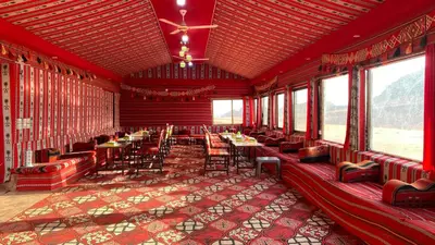 a dining room with tables and chairs and windows at Desert Gate Camp in Wadi Rum