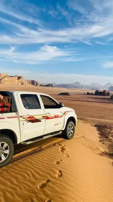 a white truck parked in the sand in the desert at camp scylla Wadi Rum in Wadi Rum