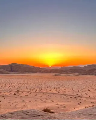 a sunset in the desert with the sun setting at camp scylla Wadi Rum in Wadi Rum