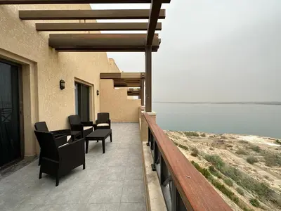 a balcony of a house with chairs and a view of the water at Dead Sea view Elite apartment Samara Resort traveler award 2024 in Sowayma