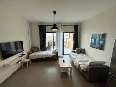 a living room with a couch and a tv at Dead Sea view Elite apartment Samara Resort traveler award 2024 in Sowayma