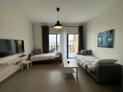a living room with a couch and a tv at Dead Sea view Elite apartment Samara Resort traveler award 2024 in Sowayma