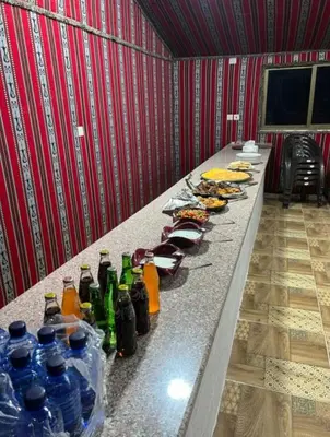 a long table with bottles of drinks and food at Wadi Rum alsultan Camp in Wadi Rum