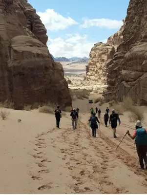 a group of people walking through the desert at Wadi Rum alsultan Camp in Wadi Rum